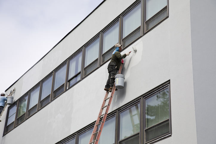 Painter rolling paint reaching to cover