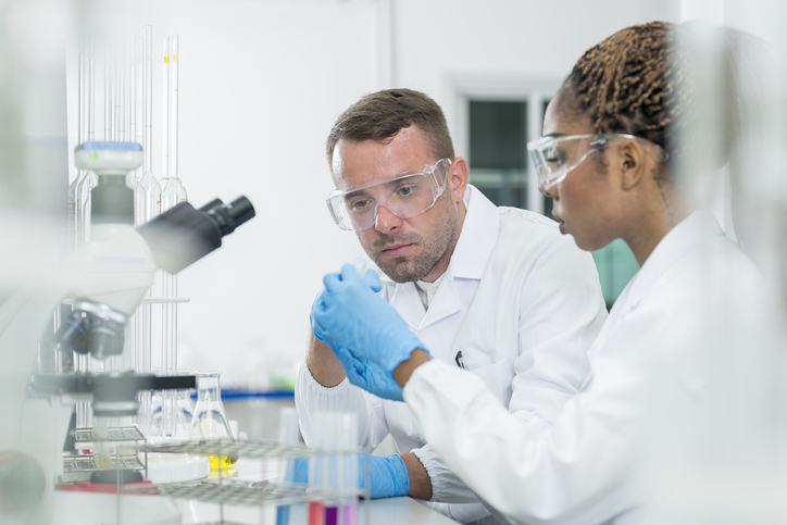 Two scientists standing in the laboratory and discussing data from experiment together.