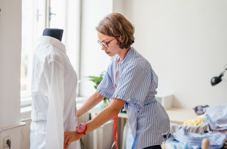Seamstress adjusting new fashion garment on a mannequin.