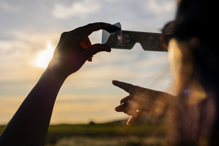 Person holding solar eclipse glasses, protecting eyes while watching sun during astronomical event